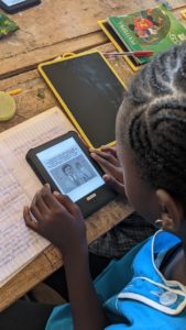 Petite fille lit une BD sur une liseuse à son bureau à l'école au Sénégal