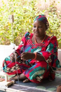 Femme nigériane assise devant son métier à tisser