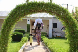 Une maman et son enfant rentrent à la maison, la maman porte du linge prore