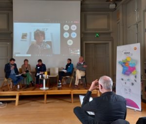 Des membres des RRMA sont assis sur une estrade pour une présentation. 