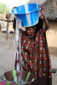 Une femme vide une bassine d'eau dans une autre au Mali.